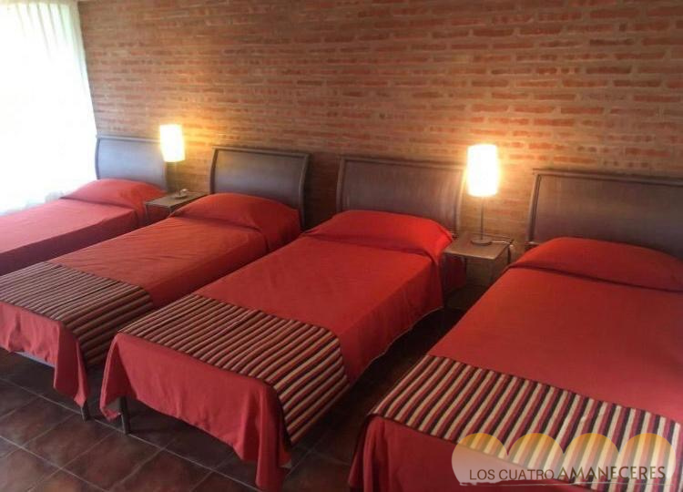 Habitación triple con camas y paredes de ladrillo